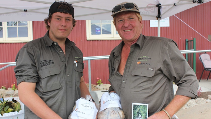 Nathaniel from the Pathfinders program and Charlie Winter from Tilbuster Station hold bags of potatoes.
