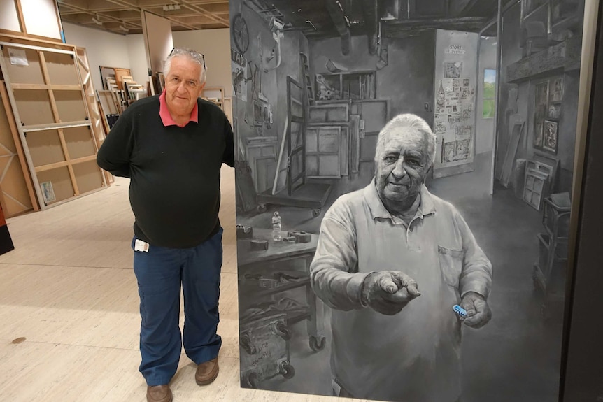 A man standing next to a black and white portrait of himself which has been entered into the Archibald Prize.