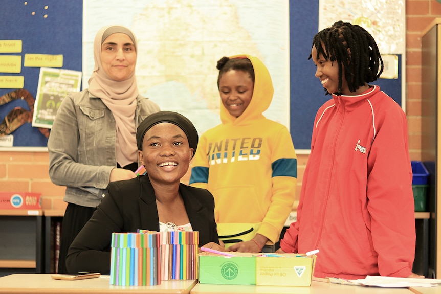 Four women from different cultures inside a school room.