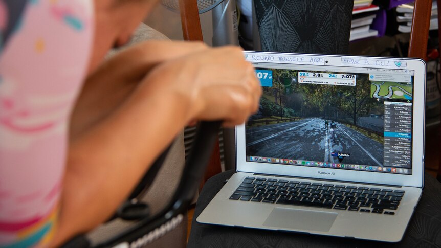 Sarah Gigante trains on an exercise bike with a race simulation on her laptop.