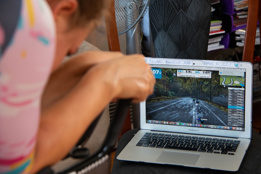 Sarah Gigante trains on an exercise bike with a race simulation on her laptop.
