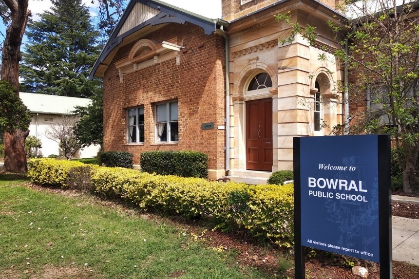 A sign out the front of an historic school building.