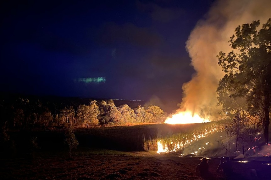 Looking over a cane paddock on fire at night.