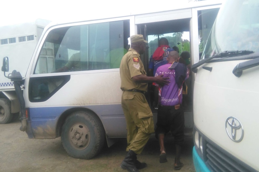 Correctional Service officers escorting some of the 99 accused onto a bus to take them to remand,  23 March 2017