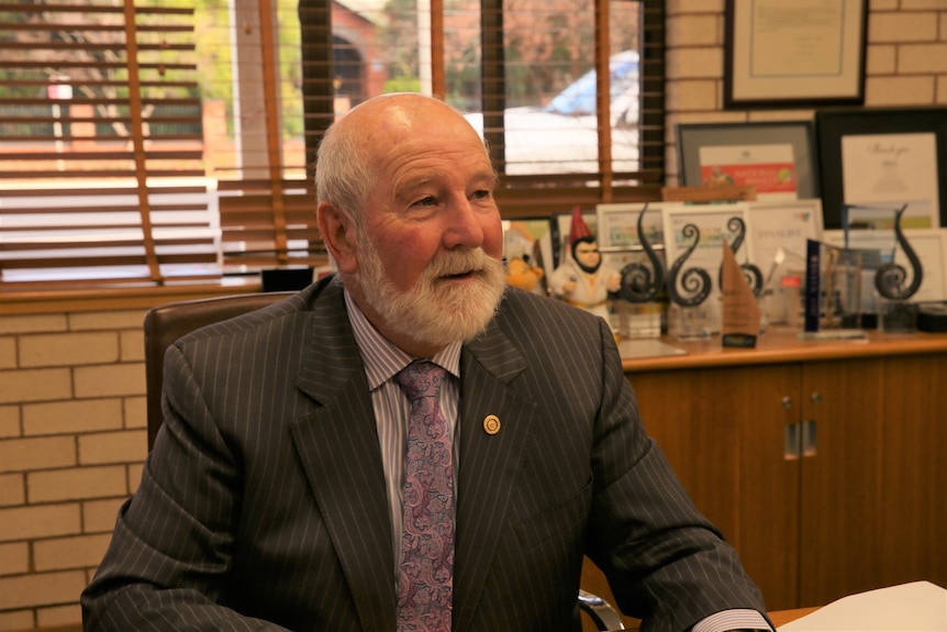 Parkes Shire Mayor Ken Keith in office. He is wearing a dark suit, striped purple shirt and patterned purple tie  