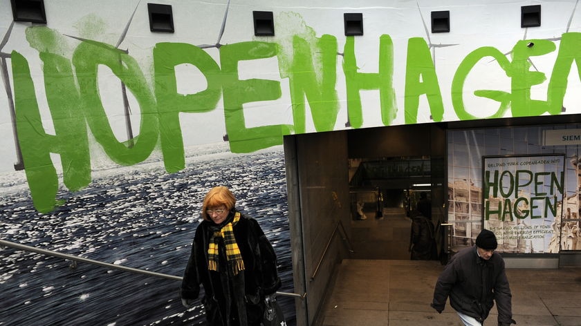 Commuters walk beneath a logo of 'Hopenhagen' as they leave a metro station in Copenhagen