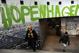 Commuters walk beneath a logo of 'Hopenhagen' as they leave a metro station in Copenhagen