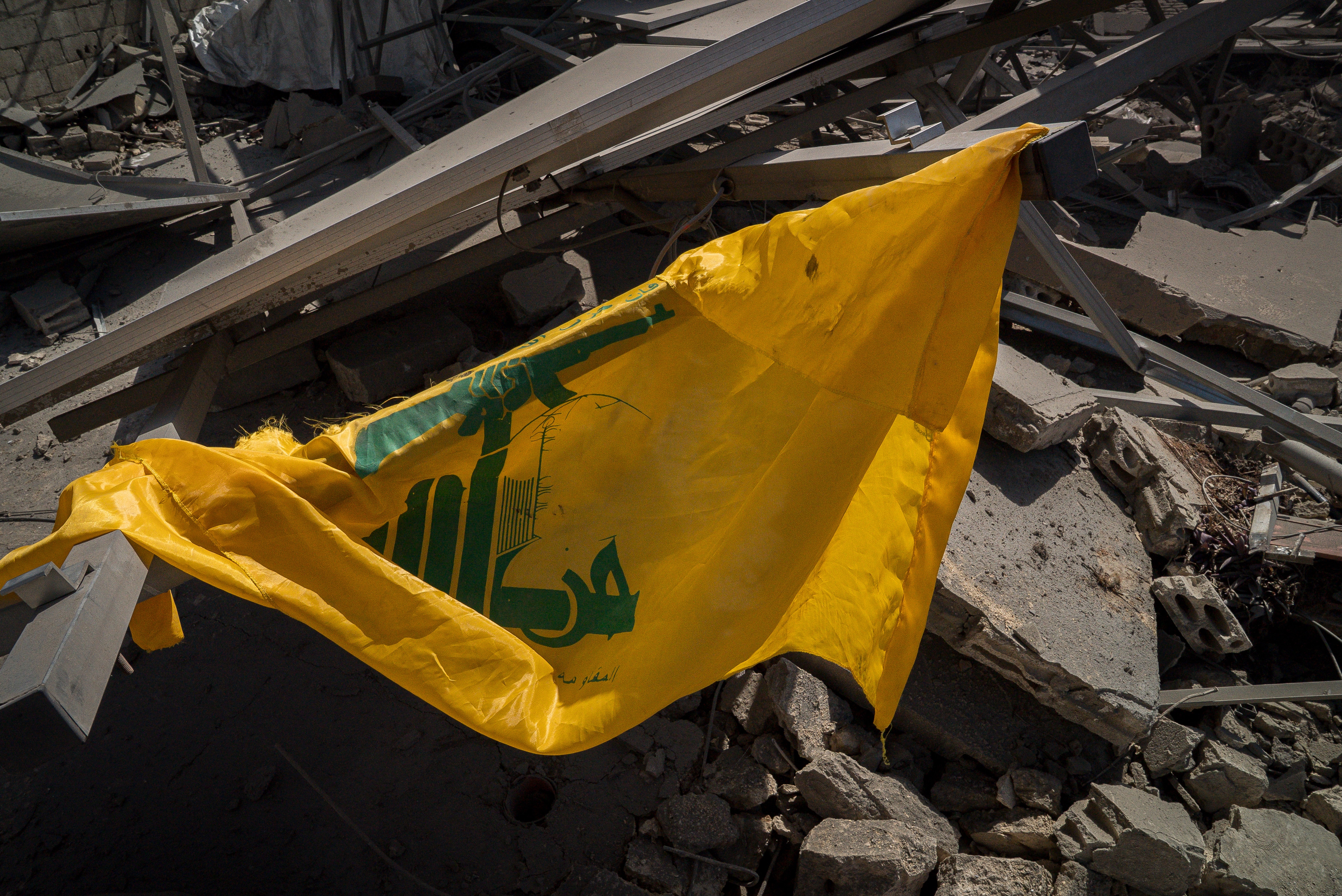 una bandera amarilla y verde colgada sobre escombros y rocas.