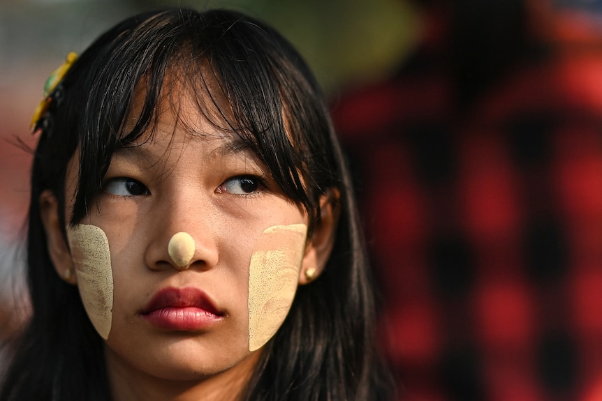 A girl has gold square marks and a gold dot on her nose.