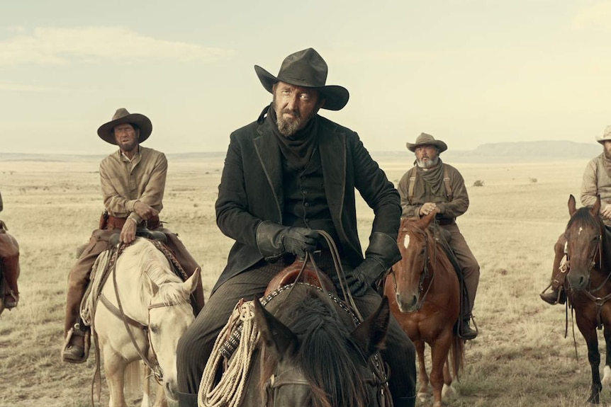 Posse of men on horses wearing Wild West clothing, washed out