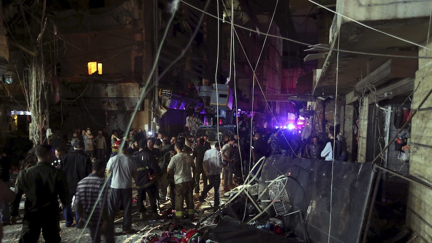 Residents inspect a damaged area caused by two explosions in Beirut's southern suburbs.