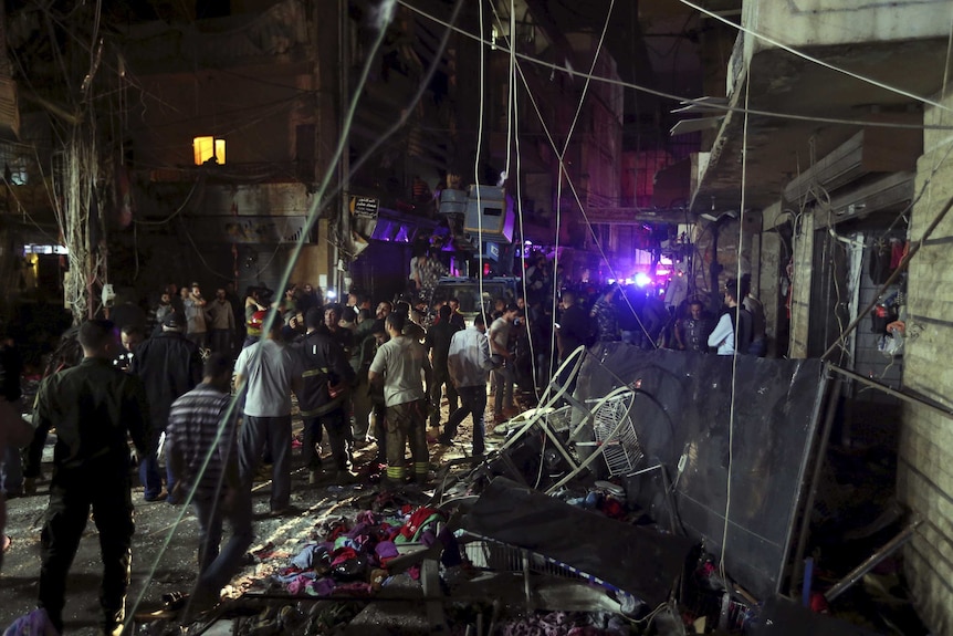 Residents inspect a damaged area caused by two explosions in Beirut's southern suburbs.