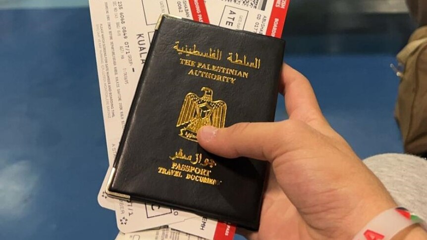 A hand holding a Palestinian passport. 