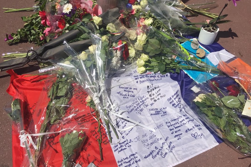 Flowers are scattered across an upside-down French flag at a makeshift memorial in Nice, France.