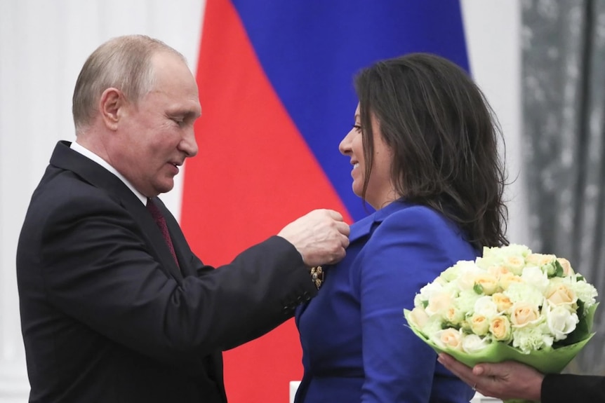 Putin presents a woman with flowers.