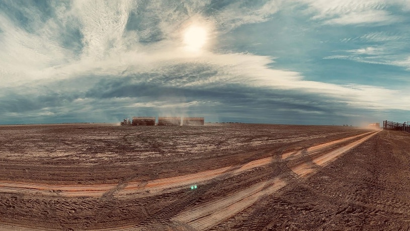 A dusty truck moves across the land