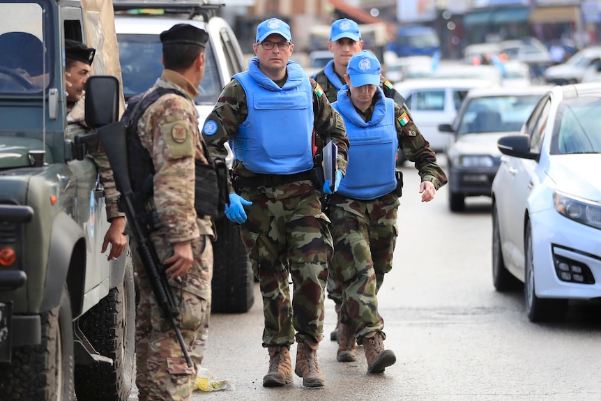 Man and woman in bright blue bulletproof vests walking