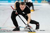 Russian athlete Alexander Krushelnitsky sweeps ice during a mixed doubles curling match.