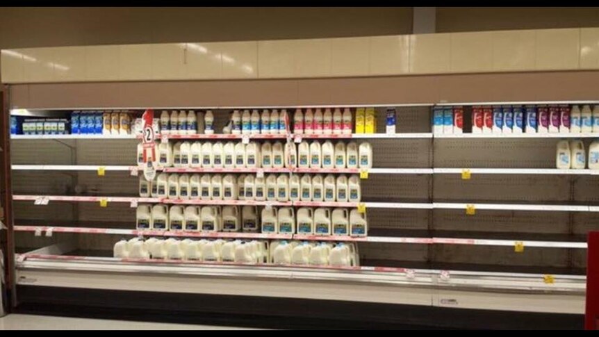 Empty fridge shelves in supermarket with just supermarket own brands left.
