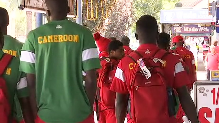 Athletes in Cameroon track suits walking down a footpath away from the camera