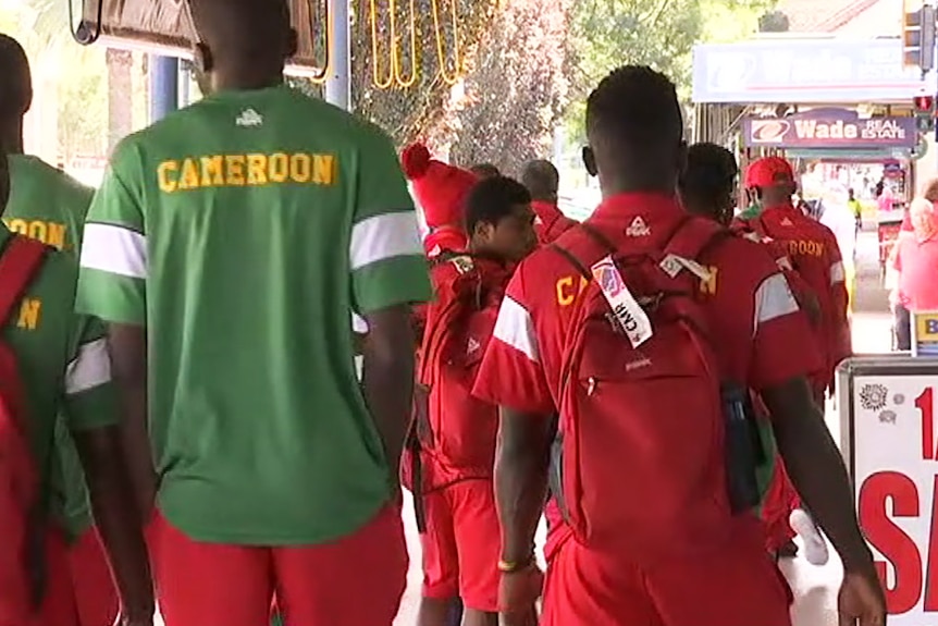 Athletes in Cameroon track suits walking down a footpath away from the camera