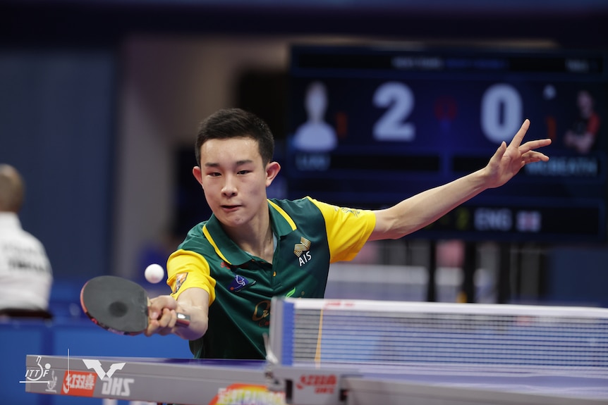 Finn Luu looks at a table tennis ball as he plays a forehand shot with his left arm splayed out behind him