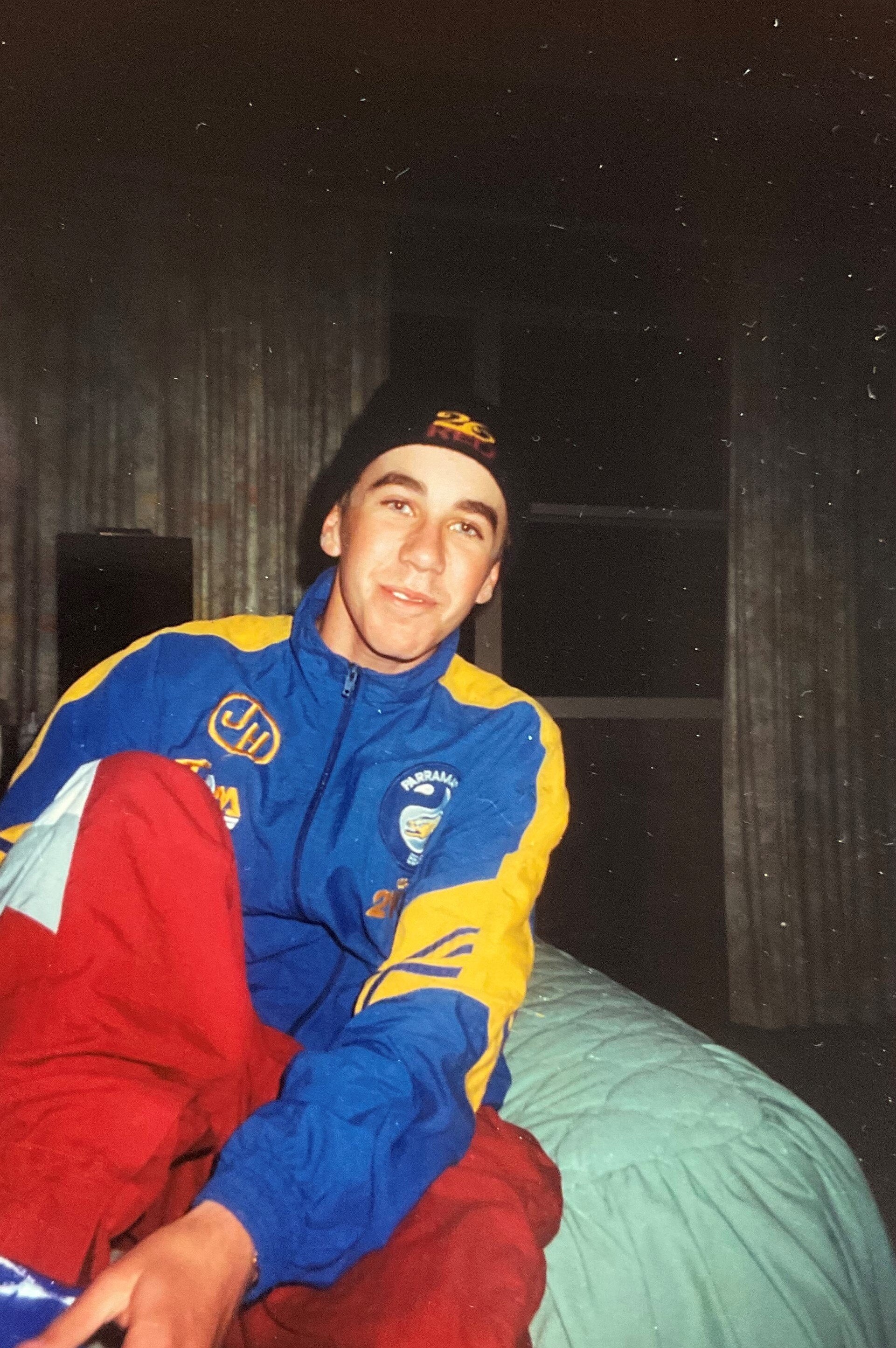 A young man smiles at the camera wearing a vintage Parramatta Eels jumper. 
