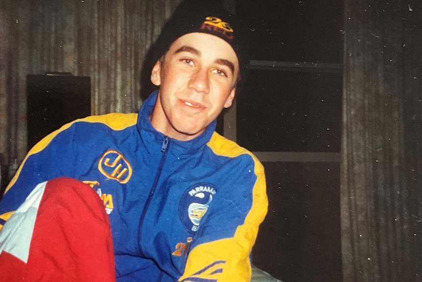 A young man smiles at the camera wearing a vintage Parramatta Eels jumper. 