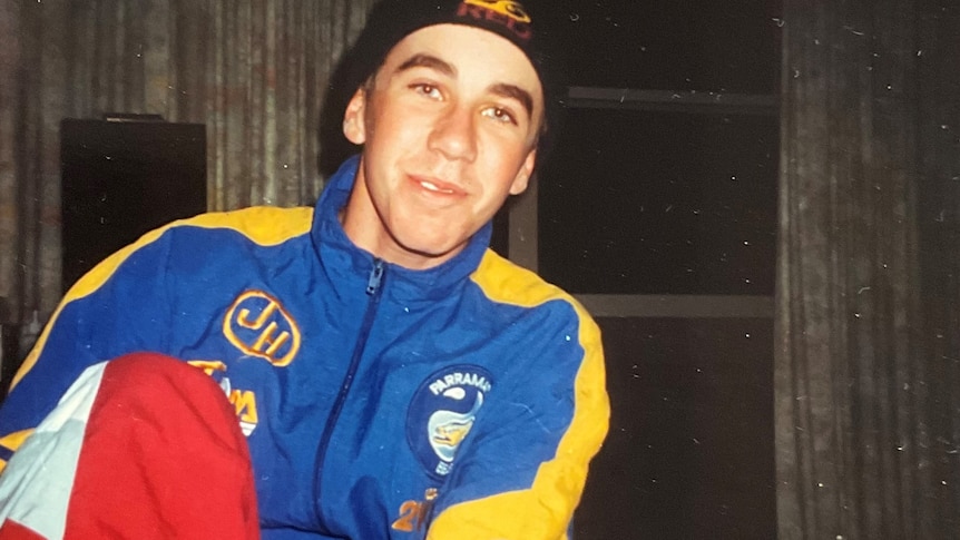 A young man smiles at the camera wearing a vintage Parramatta Eels jumper. 