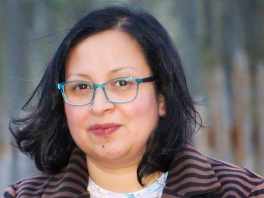 A photo of Nusrat Islam wearing glasses, in front of a blurry background.