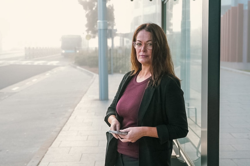 A woman standing at an empty bus stop 