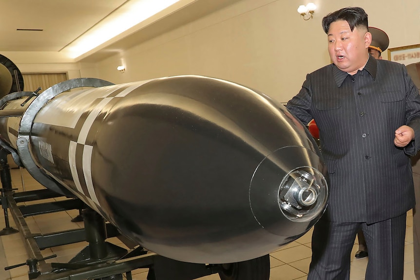Kim Jong Un stands next to a nuclear warhead