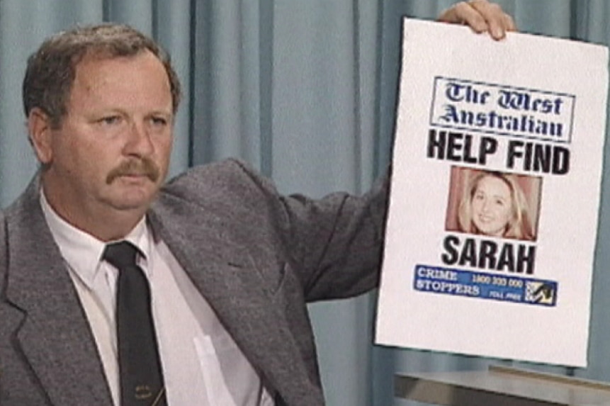 A detective holds up a newspaper poster captioned "Help find Sarah".