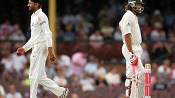 Indian bowler Harbhajan Singh walks past Australian batsman Andrew Symonds on his way back to his bowling mark during day fou...