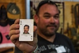 Brian Willcox holds Saddam Hussein ace of spades playing card