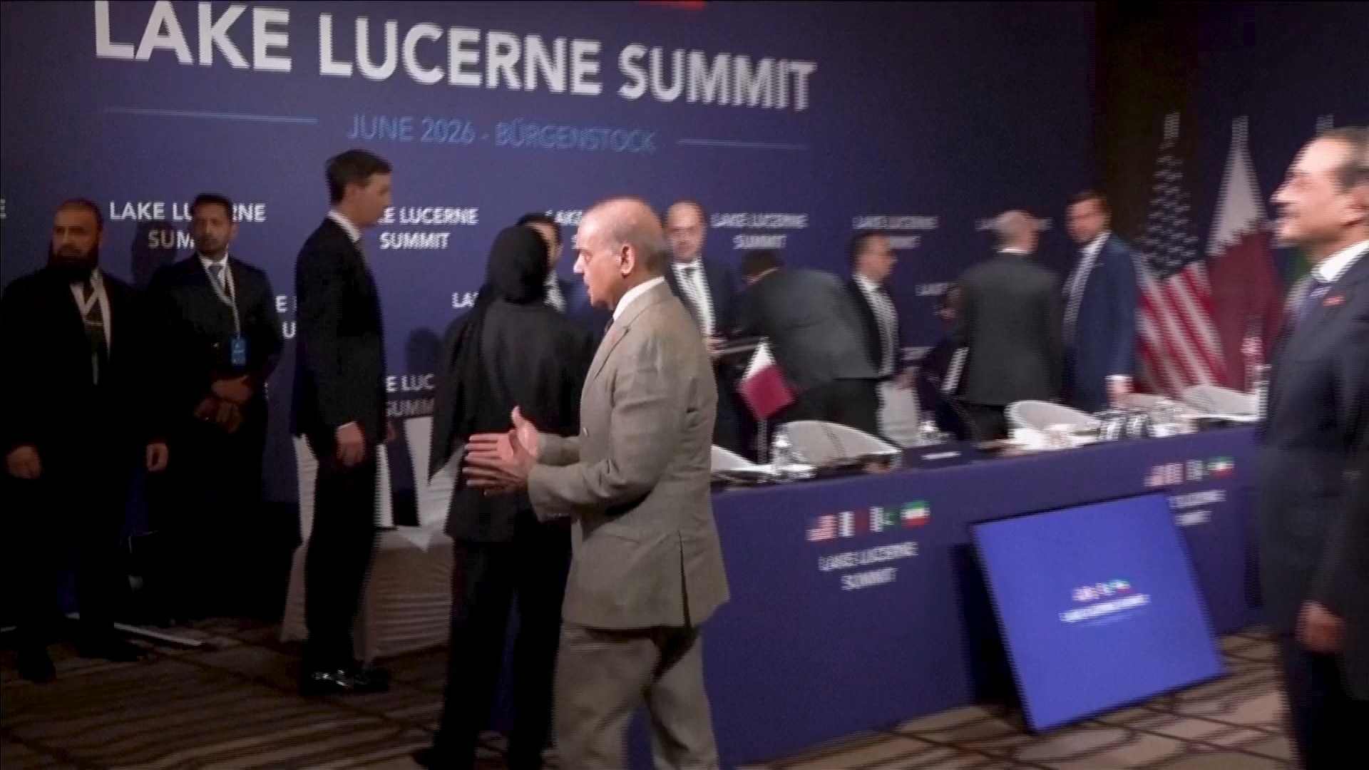 JD Vance stands near a sign watching as Iran's delegation walks out of the room.