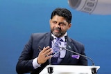 Aiyaz Sayed-Khaiyum stands in front of a large image of a Fiji Airways jet.