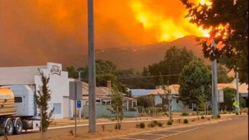 A hill on fire in the background with the Walwa Bush Nursing Centre in the foreground.