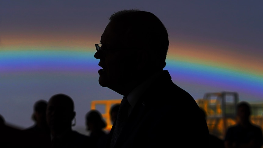 A profile picture of scott morrison in silhouette with a rainbow behind him