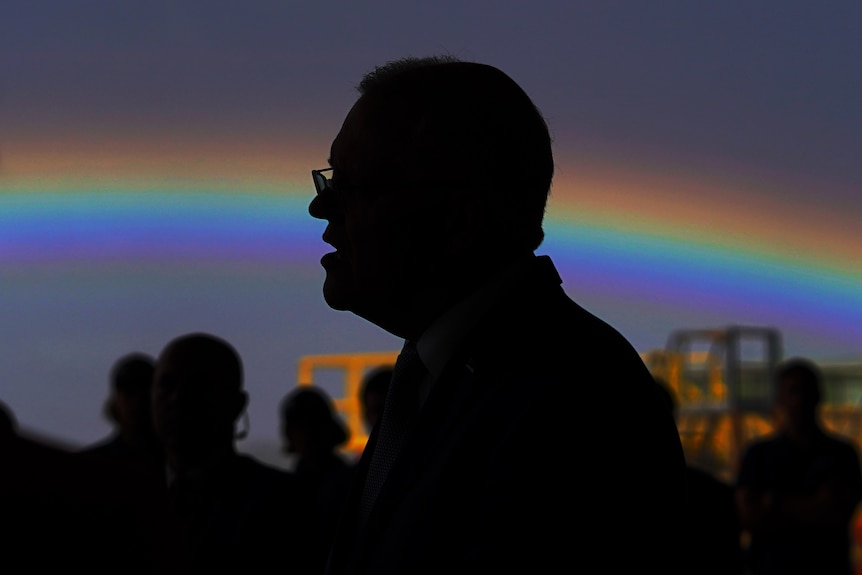 A profile picture of scott morrison in silhouette with a rainbow behind him