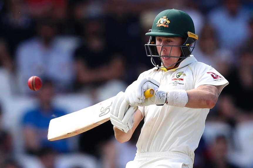 Australia batsman Marnus Labuschagne leans back as he pushes his bat at a cricket ball. He is sticking his tongue out.