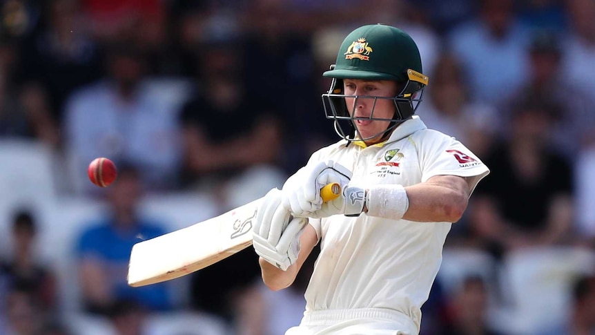 Australia batsman Marnus Labuschagne leans back as he pushes his bat at a cricket ball. He is sticking his tongue out.