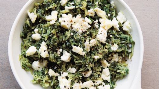 Greek spinach rice with crumbled feta, in a white dish, with a grey slate.