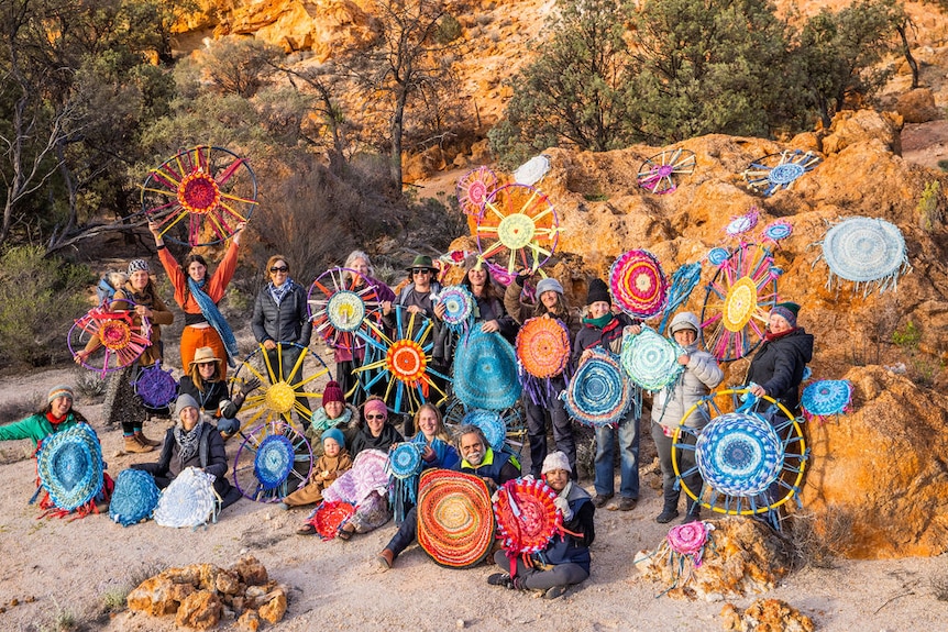 A group of people holding woven blankets 
