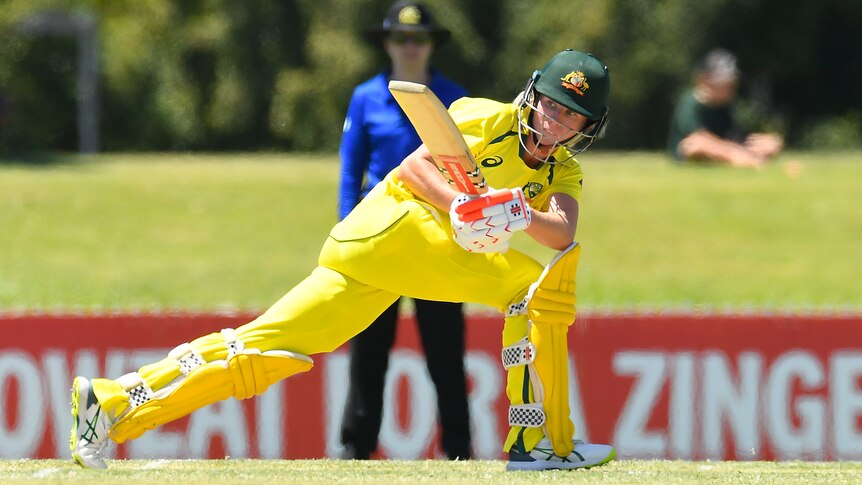 Beth Mooney sweeps the ball around the corner wearing yellow cricket kit