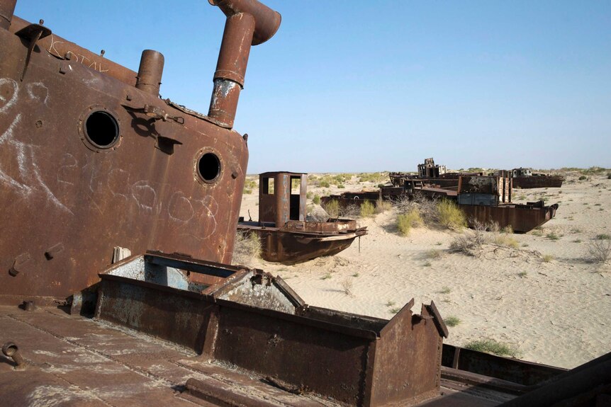 A rusted fishing boat sits idle in dunes on the dried up lake bed of the Aral Sea.