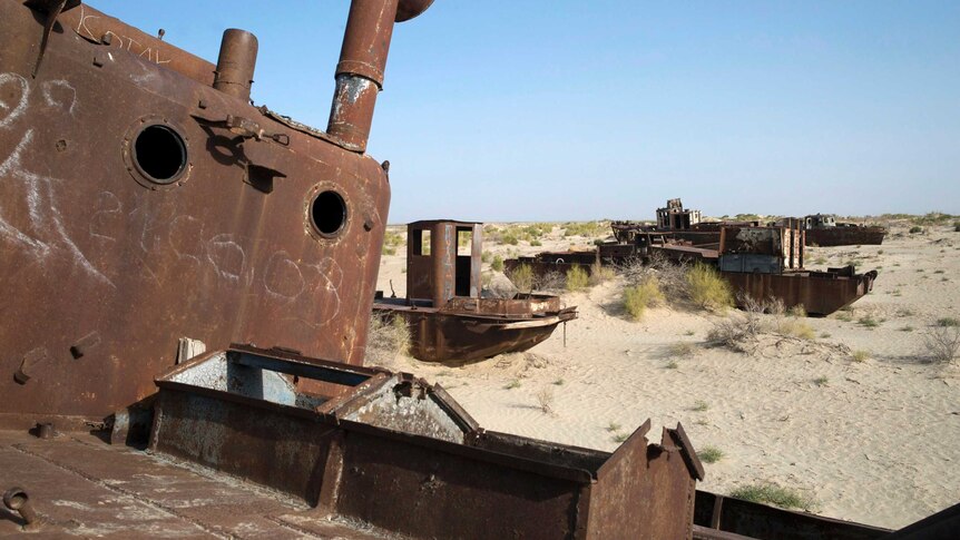 A rusted fishing boat sits idle in dunes on the dried up lake bed of the Aral Sea.