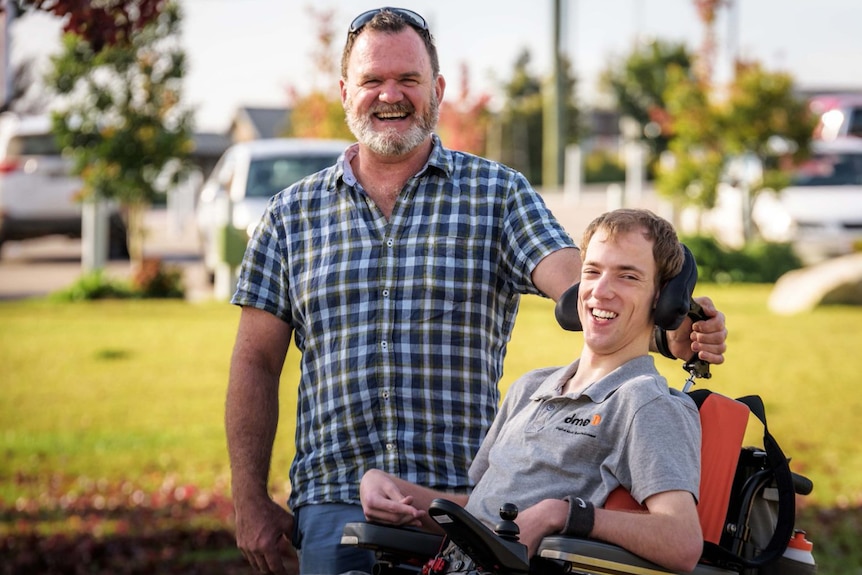 A man sits in a wheelchair next to his support worker