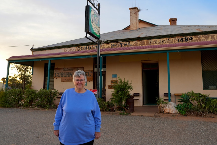 An elderly white woman wearing a blue shirt in front of an online pub.