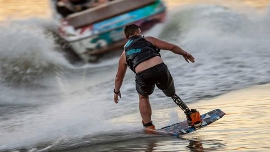 A man wakeboarding with a prosthetic limb.